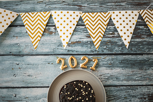 Hanging party flags and cakes isolated on blue wooden background, decorate items for festival, celebrate event, birthday, Christmas and 2021 New Year background