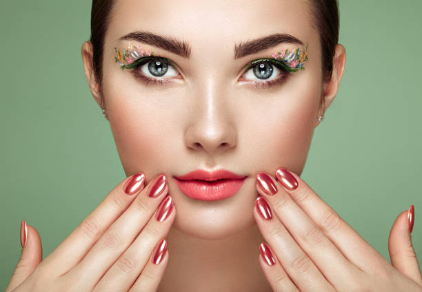 Beauty brunette woman with perfect makeup. Glamour girl. Red lips and nails. Perfect eyebrows. Skin care foundation. Beauty girls face isolated on green background. Fashion photo