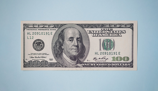 One hundred dollar banknote on a blue background. Business and finance. Benjamin Franklin