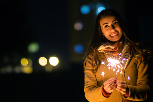 Portrait of a happy woman holding s sparkler on Noche de Velitas, a traditional celebration  in Colombia that takes places on the 7th of December and marks the beginning of Christmas time