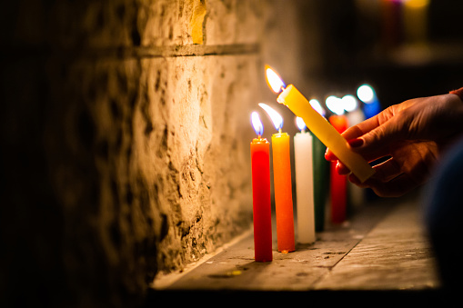 Close-up on a woman lighting candles outdoors during the Noche de Velitas celebration that takes places on the 7th of December in Colombia and marks the beginning of Christmas time