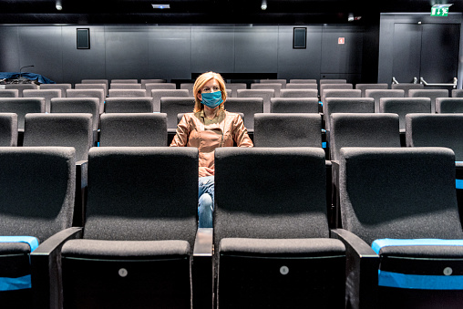 Woman with Protective Mask During Covid 19 Sitting in Empty Theater