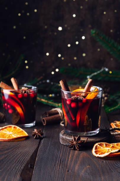 weihnachtsglühwein mit preiselbeeren, orangen und gewürzen auf rustikalem holzhintergrund - glühwein stock-fotos und bilder