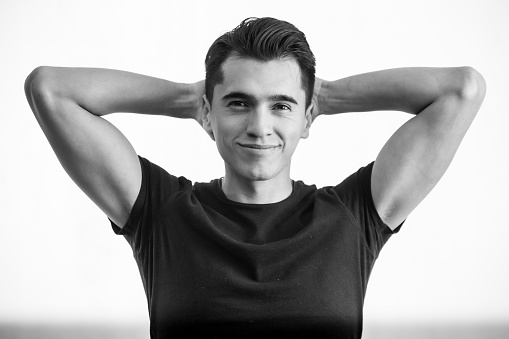 Young man wearing a black t-shirt on a white background, performing different poses of leadership, entrepreneurship and youth.