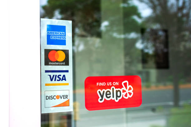 MasterCard, VISA, American Express, Discover payment options on a restaurant door MasterCard, VISA, American Express, Discover payment options advertised on a restaurant door. A red sticker decal promotes Yelp crowd-sourced reviews service - San Francisco, California, USA - 2020 american express stock pictures, royalty-free photos & images