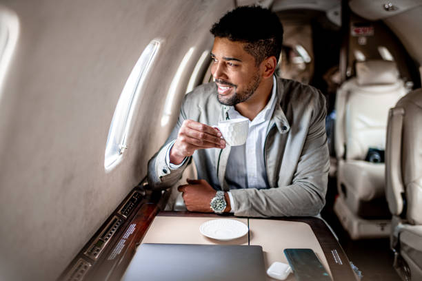 Young businessman in his private jet having coffee Young businessman holding a cup of coffee during a flight in private jet airplane while heading to a business casual trip. private jet plane stock pictures, royalty-free photos & images