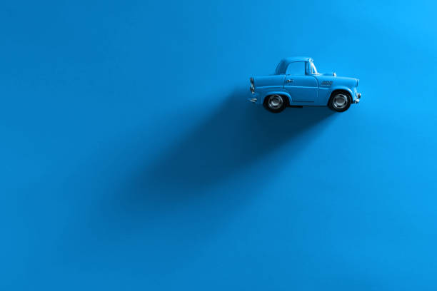 blaues spielzeugauto auf blauem hintergrund. - spielzeugauto stock-fotos und bilder