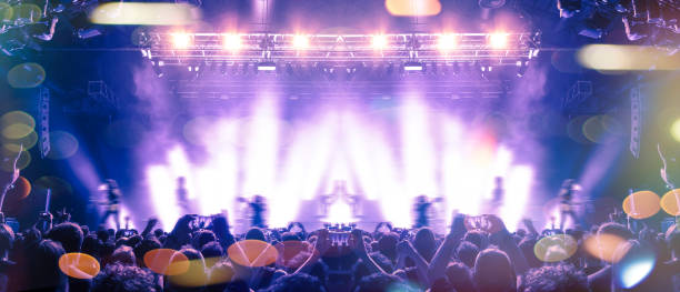 Large assembly of people in front of a large stage lit in the dark.