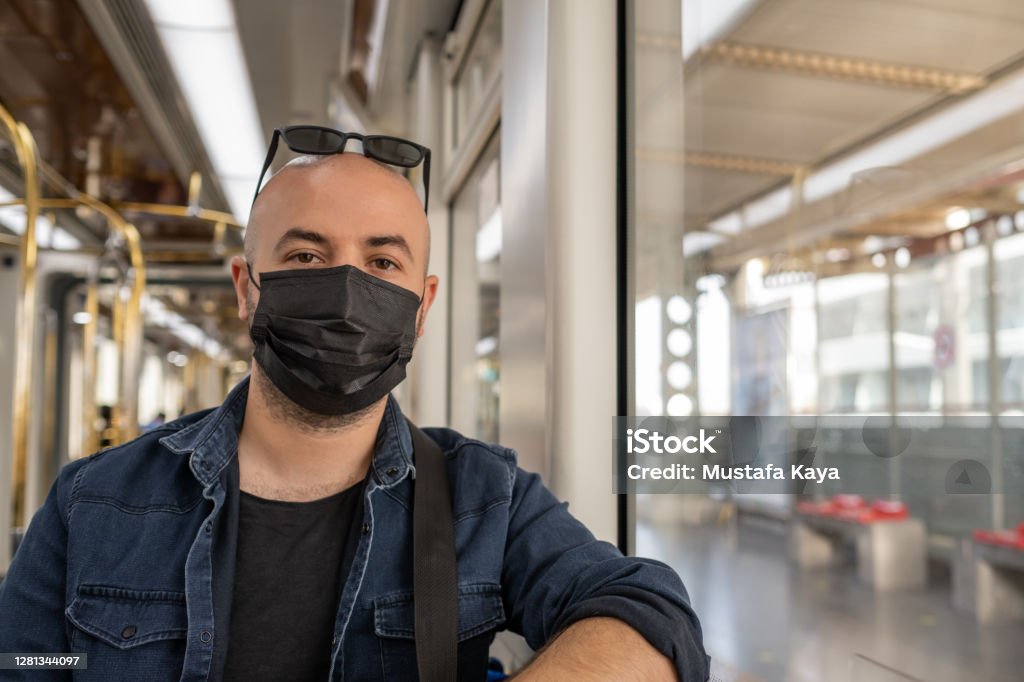 Handsome young man in black mask is traveling by subway. Black Protective Face Mask Stock Photo