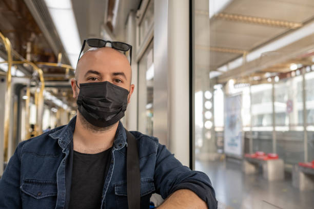 Handsome young man in black mask is traveling by subway. stock photo
