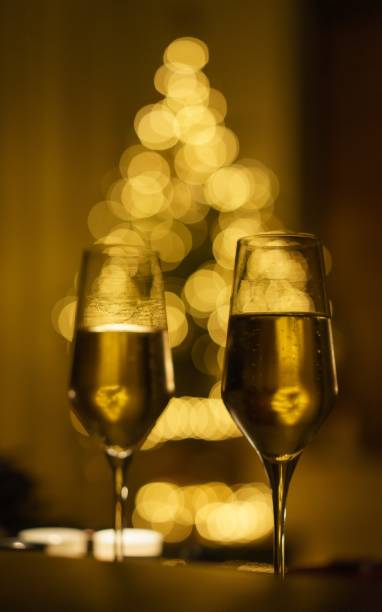 istock Celebrating New Year glasses with Christmas tree lights background. 1281355352