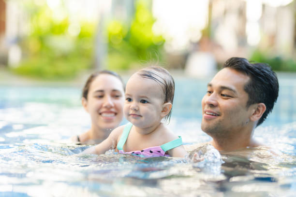 istock Cute mixed race baby playing in the pool with her mom and dad 1281355556
