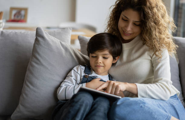 istock Mother and son at home reading an online book on a tablet computer 1281357158