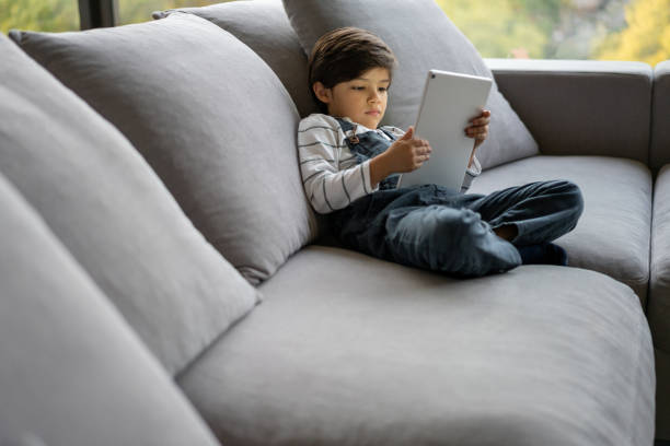 istock Boy looking bored at home playing games on a tablet computer 1281357196