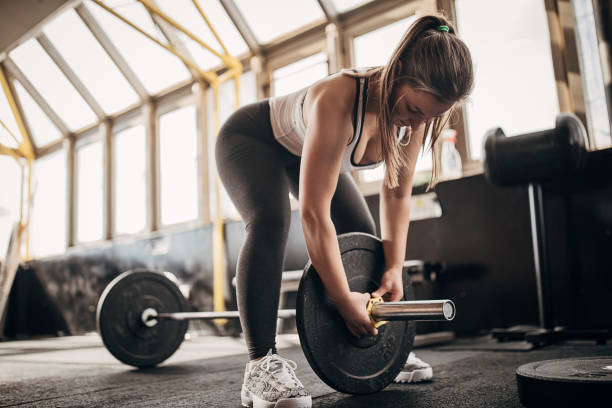 istock Fit woman preparing weights for training in gym 1281364154