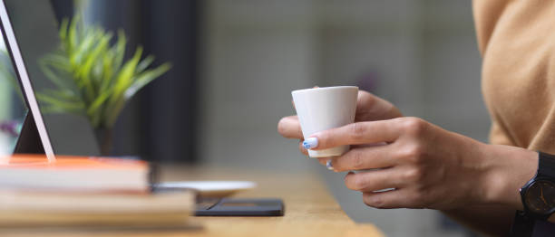 istock Side view of female hands holding coffee cup while working on wooden bar 1281367250