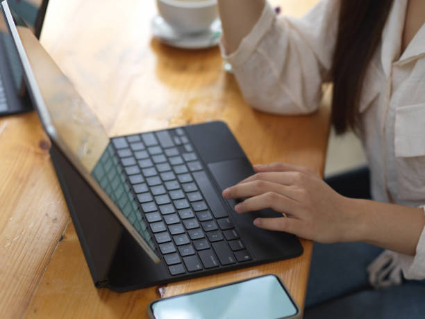 istock Female hand typing on tablet keyboard while working with smartphone in cafe 1281367912