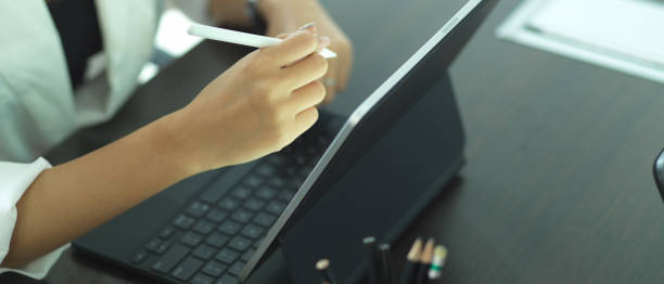 istock Female hand using digital tablet with keyboard and stylus pen on black table 1281367992