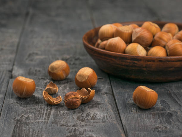 istock Clay bowl filled with large hazelnuts on a black table. 1281382838