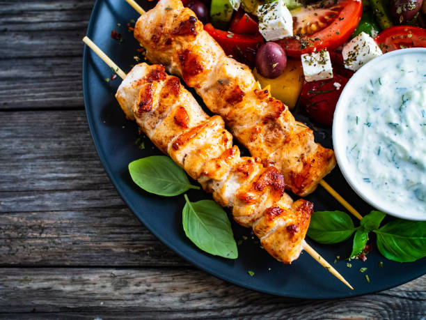 スブラキ - 木製のテーブルの上に焼き肉、ギリシャのサラダとツァツィキ - greek cuisine chicken grilled grilled chicken ストックフォトと画像
