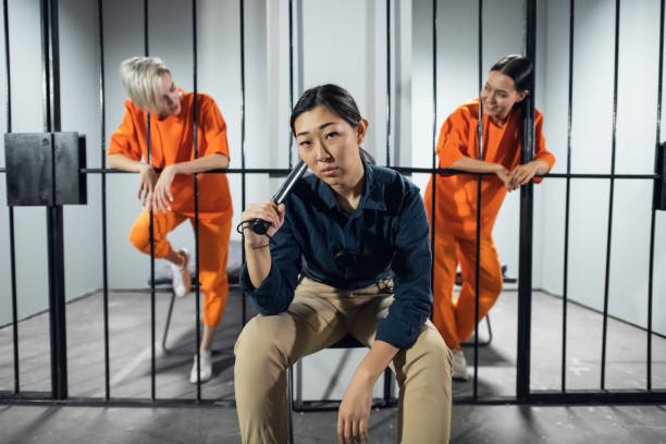 Portrait of an asian security guard against the background of two cute criminals in the cells stock photo
