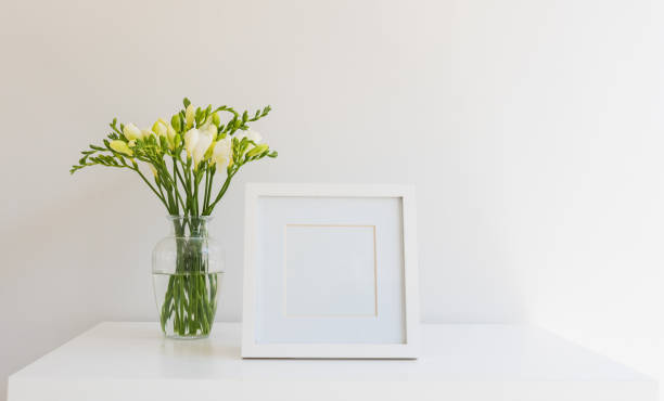 istock White freesias in vase next to blank square picture frame 1281389261