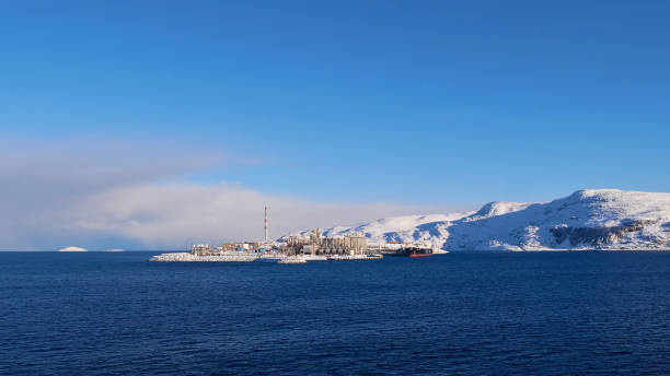 blick auf europas größten flüssigerdgasstandort (lng) auf der insel melkéya im arktischen meer mit dockingtanker und schneebedeckten bergen. - hammerfest stock-fotos und bilder