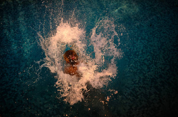 A big splash of a young girl jumping into a pool in summer.