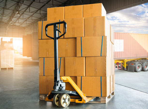 istock Cargo shipment boxes, Freight truck, Warehousing. Hand pallet jack with stack of cardboard boxes on pallet waiting to load into shipping container. Logistics and transportation. 1281399045