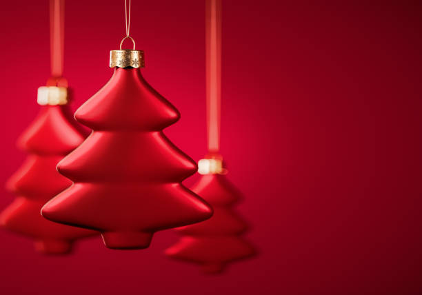 Group of three red Christmas balls. Tree shape baubles hanging on strings against burgundy red background. Christmas decoration, festive atmosphere concept. Selective focus, copy space.
