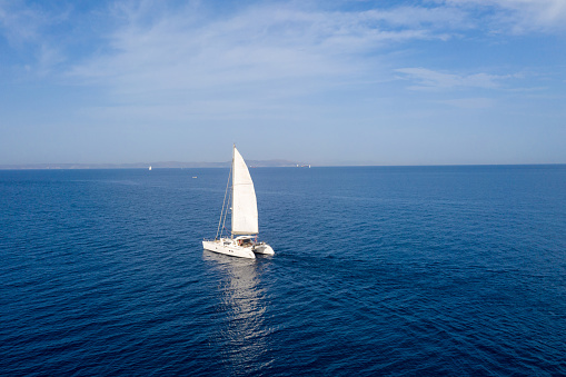 Aerial view of sailboat sailing and navigating at with slow morning breeze power using spinnaker. Photo taken with drone