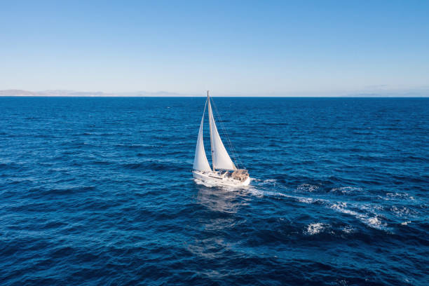 istock Sailing boat with white sails, cloudy sky and rippled sea background 1281404034