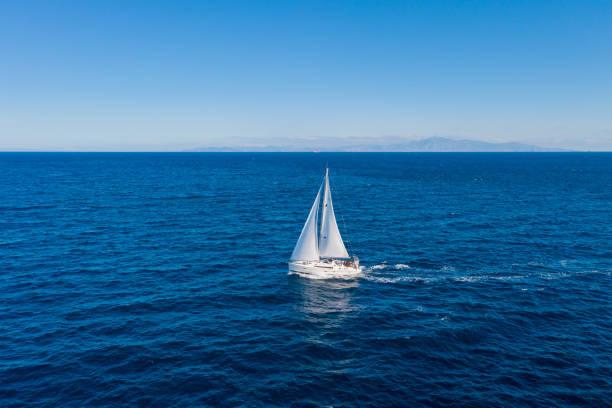 istock Sailing boat with white sails, cloudy sky and rippled sea background 1281404041