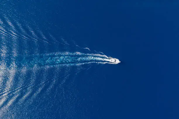 Motorboat, luxury speed yacht navigating on rippled sea background, white wake. Summer vacation in Aegean sea Greece. Aerial drone top view