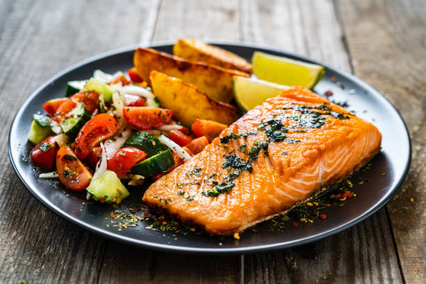 bistecche di salmone fritto, patate fritte e verdure fresche su tavola di legno - salmone arrosto foto e immagini stock