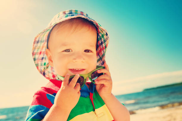istock Little boy smiling at the beach in hat with sunglasses 1281409189