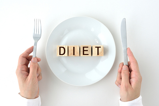 Wooden blocks with DIET words on white plate with human's hands