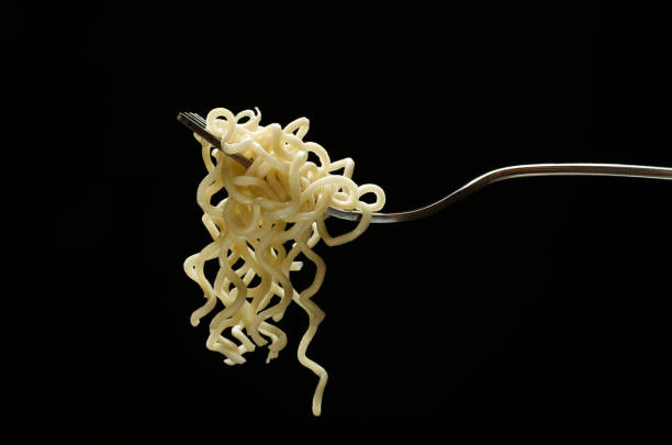 istock Closeup of cooked noodles on the silver fork against dark background 1281411343