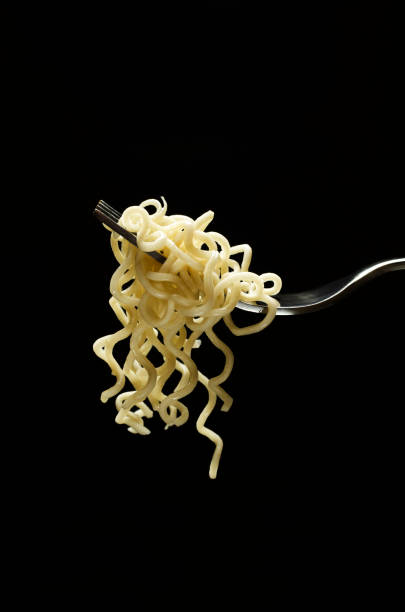 istock Vertical image.Delicious cooked noodles on the fork against black background 1281411631