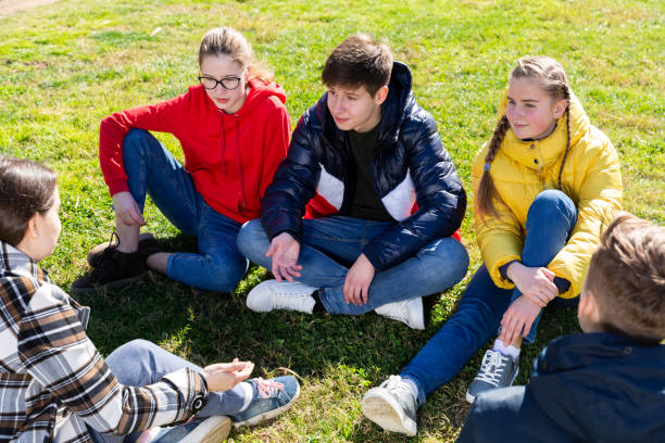 istock Smiling teenages discussing on green grass 1281412273