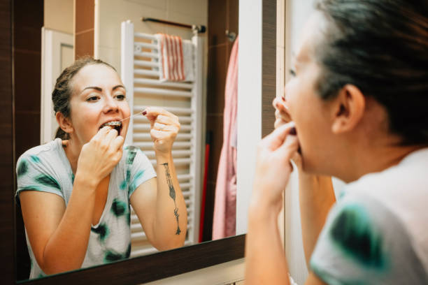 istock Woman cleaning her teeth's with dental floss 1281413149