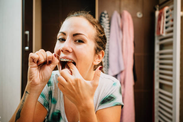 woman cleaning her teeth's with dental floss - dental hygiene dental equipment brushing teeth dental floss imagens e fotografias de stock