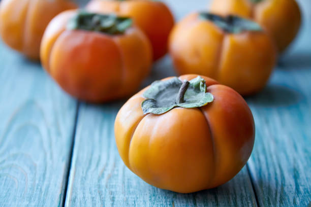 istock Ripe fresh persimmon on blue wooden rustic background. Close-up, selective focus 1281413256
