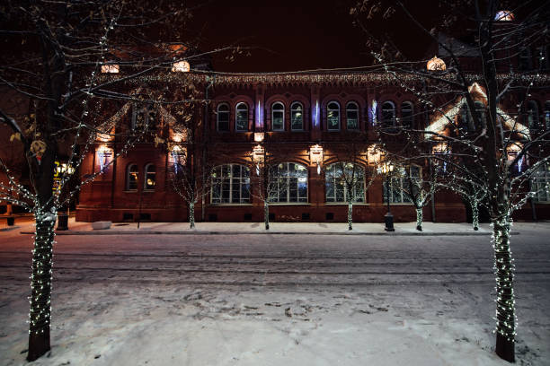 istock Trees and buildings are decorated with white garlands and glow at night. 1281414086