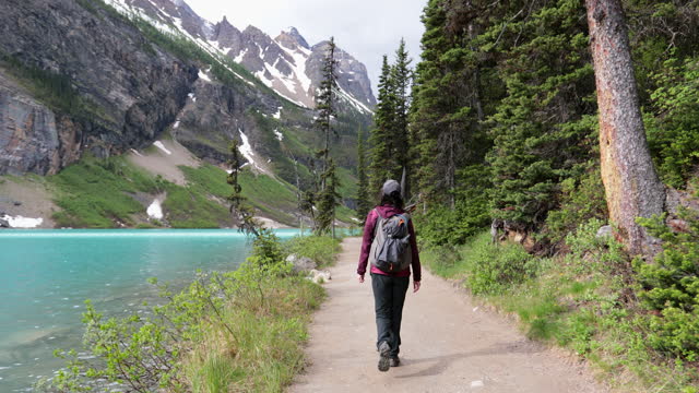 Young Woman Walking on Lake Louise Lakeshore Trail in the Morning, Alberta, Canada
