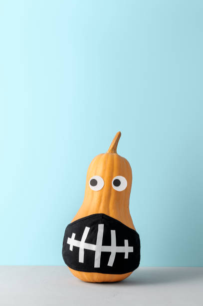 istock Funny pumpkin with face protective mask on pastel blue background with copy space. 1281415280