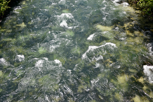 The water of the mountain river foams around the rocks and stones