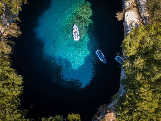 Couple of tour boats floating on the surface of clear water in cave Melissani stock photo