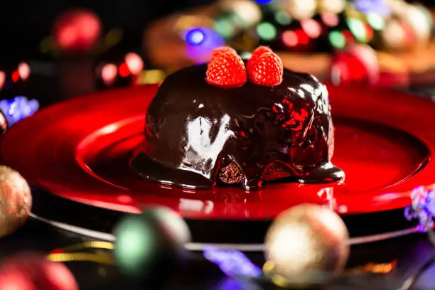 Festive photo of a Christmas Pudding on a vibrant red plate. Dessert background.