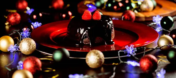 Festive photo of a Christmas Pudding on a vibrant red plate. Dessert background.